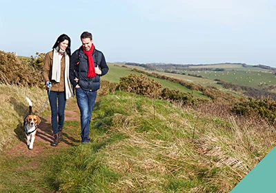 A couple walking a dog outdoors